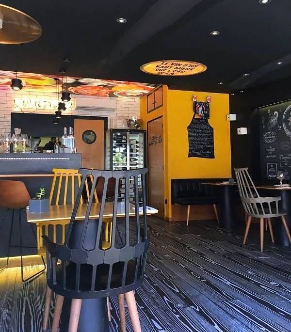 Intérieur moderne d'un restaurant avec bar, chaises jaunes et noires, décoration épurée